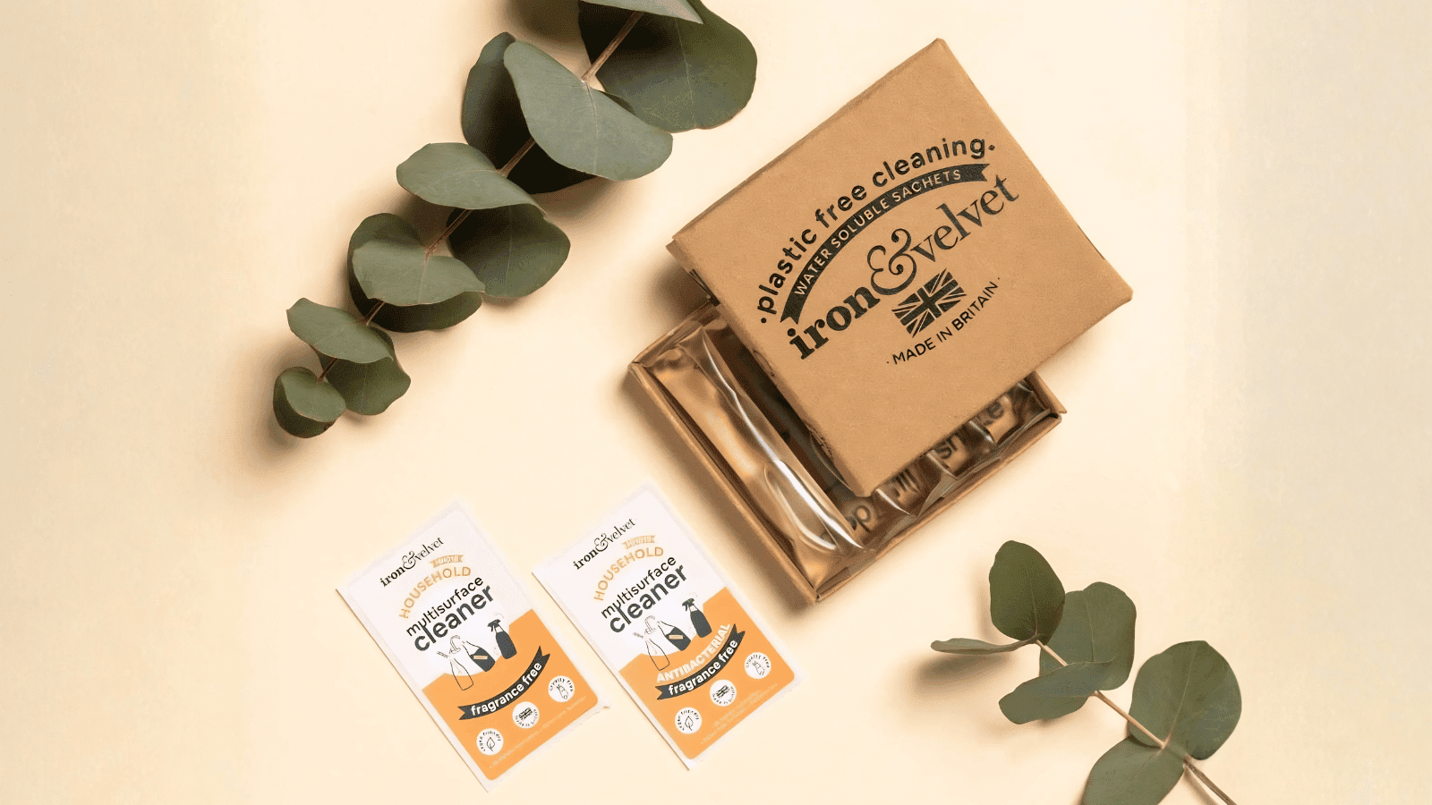 Iron and Velvet packaging on light yellow background with some decorative eucalyptus.