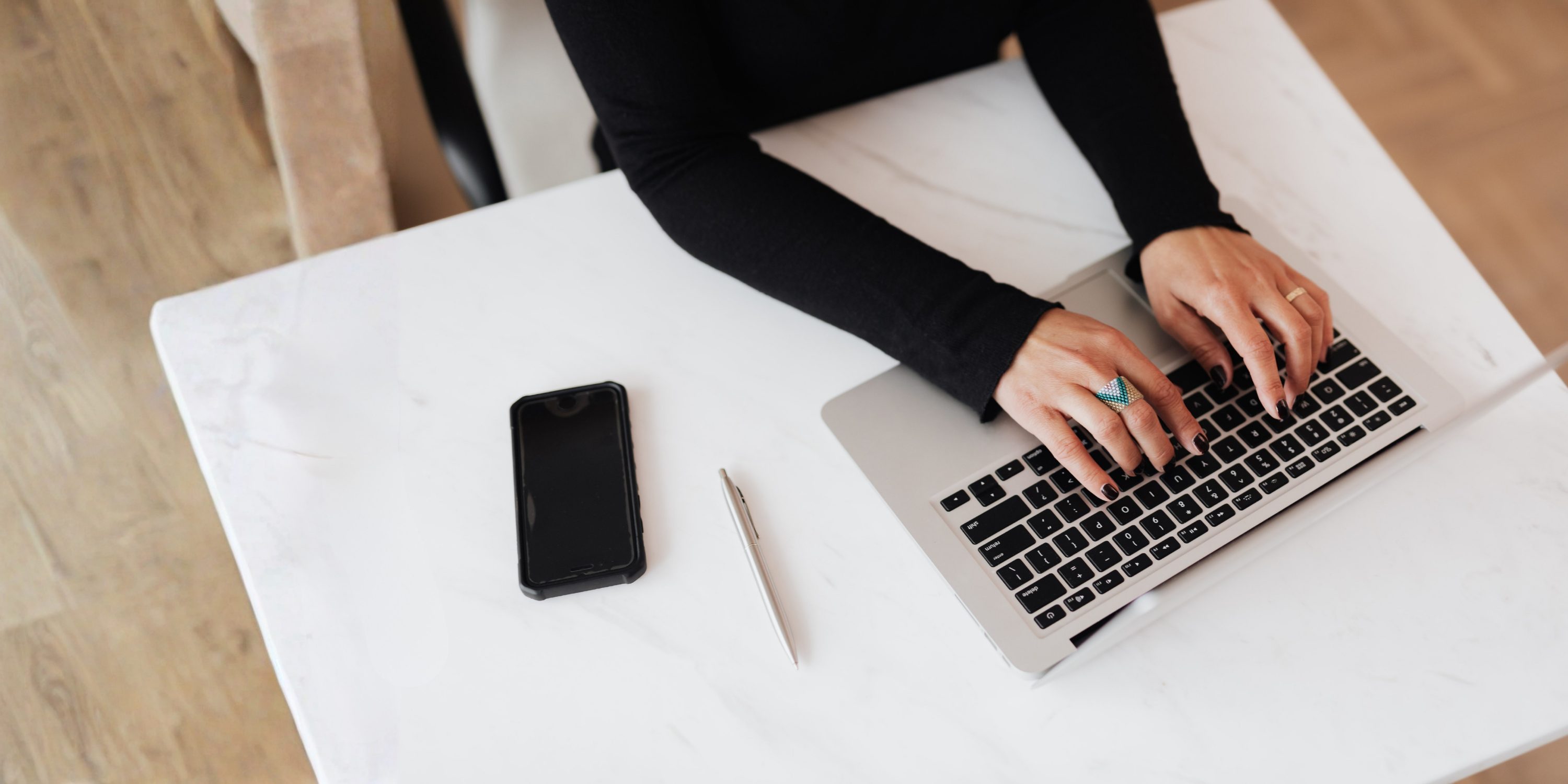 Crop faceless woman using laptop at desk in light office